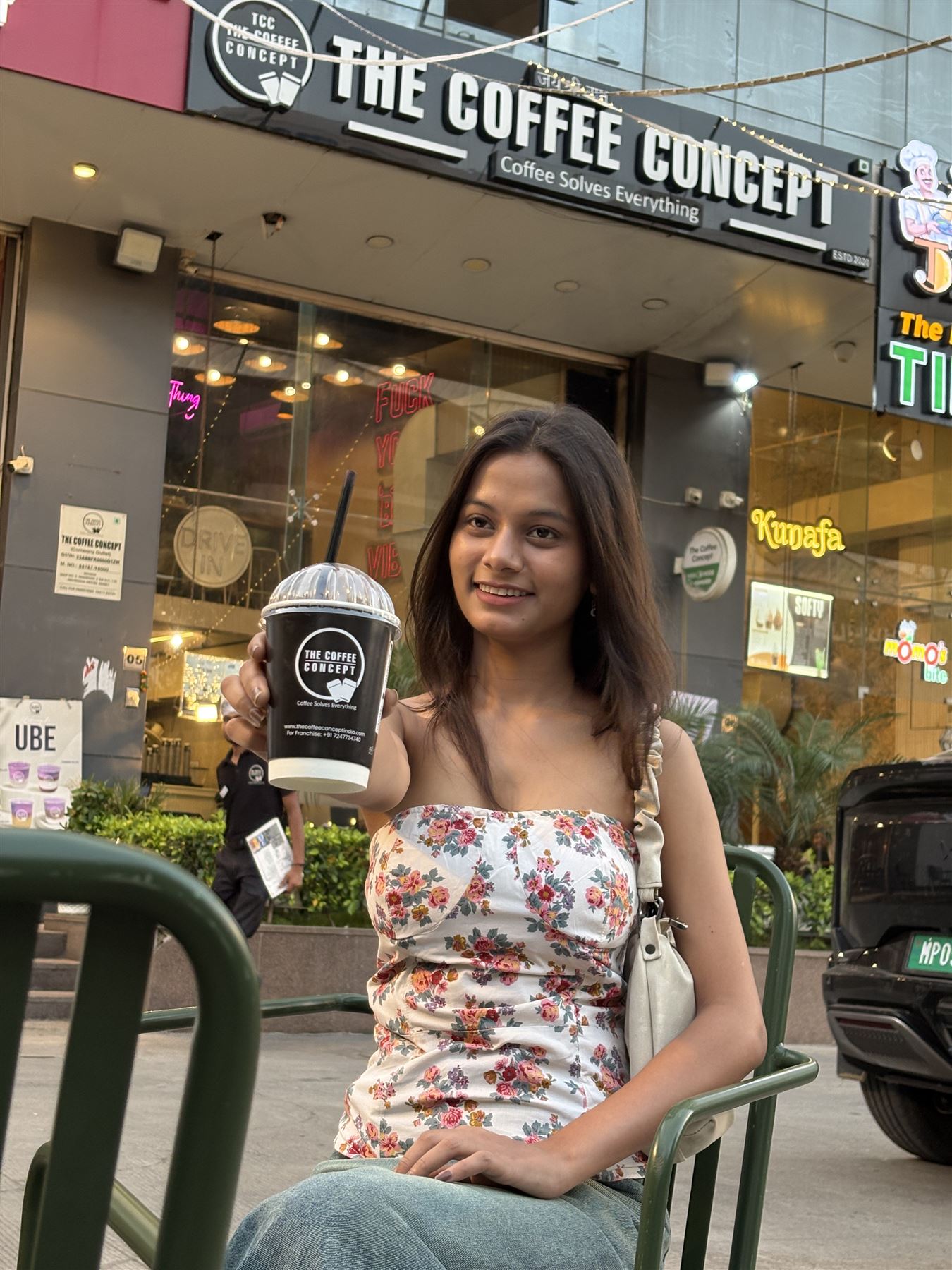 A guest raising her drink outside a TCC café at sunset